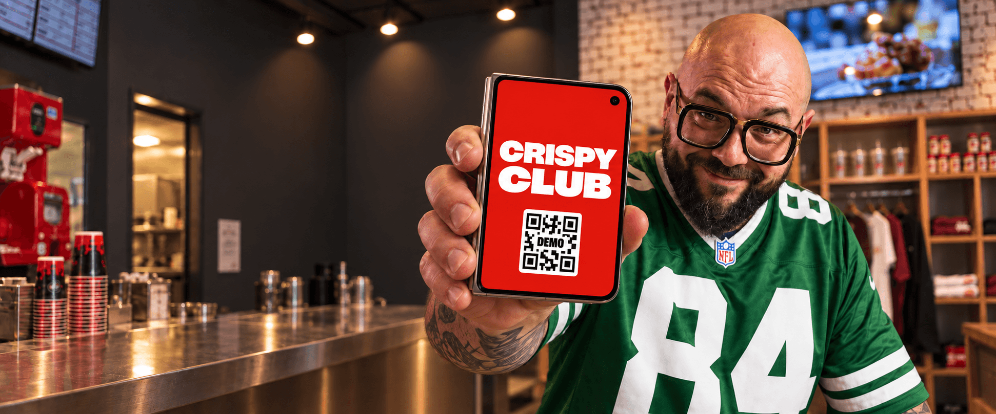 Mocho holds an iPhone showing a Crispy Club demo card close to the camera inside the Via Melzo store.