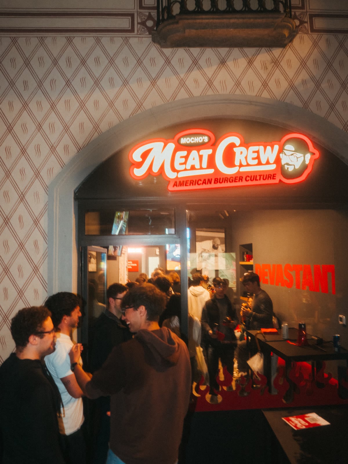 People queuing under the Meat Crew sign on Via Cesare Cantù, Como
